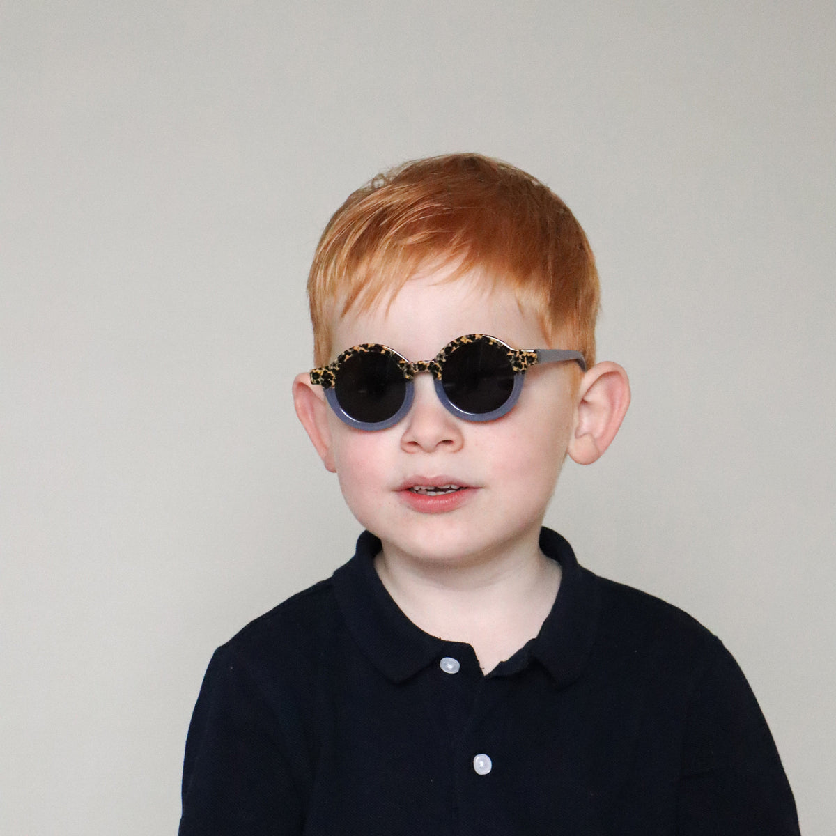 Paire de lunettes de soleil bébé catégorie 4, monture en TPEE effet transparent couleur bleue avec motif léopard sur le haut. Mise en situation portée de face