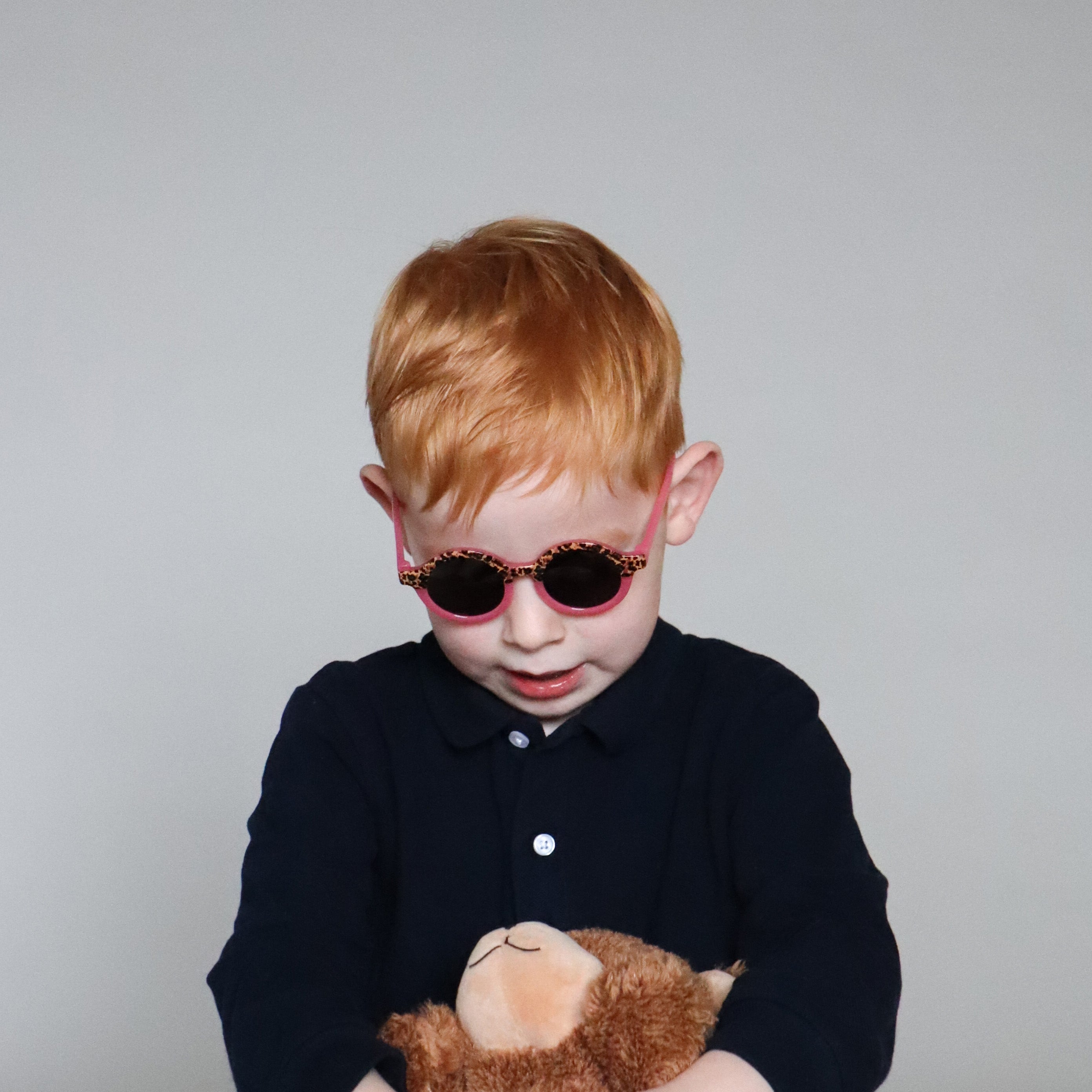 Paire de lunettes de soleil bébé catégorie 4, monture en TPEE effet transparent couleur rose avec motif léopard sur le haut. Mise en situation rapprochée de face