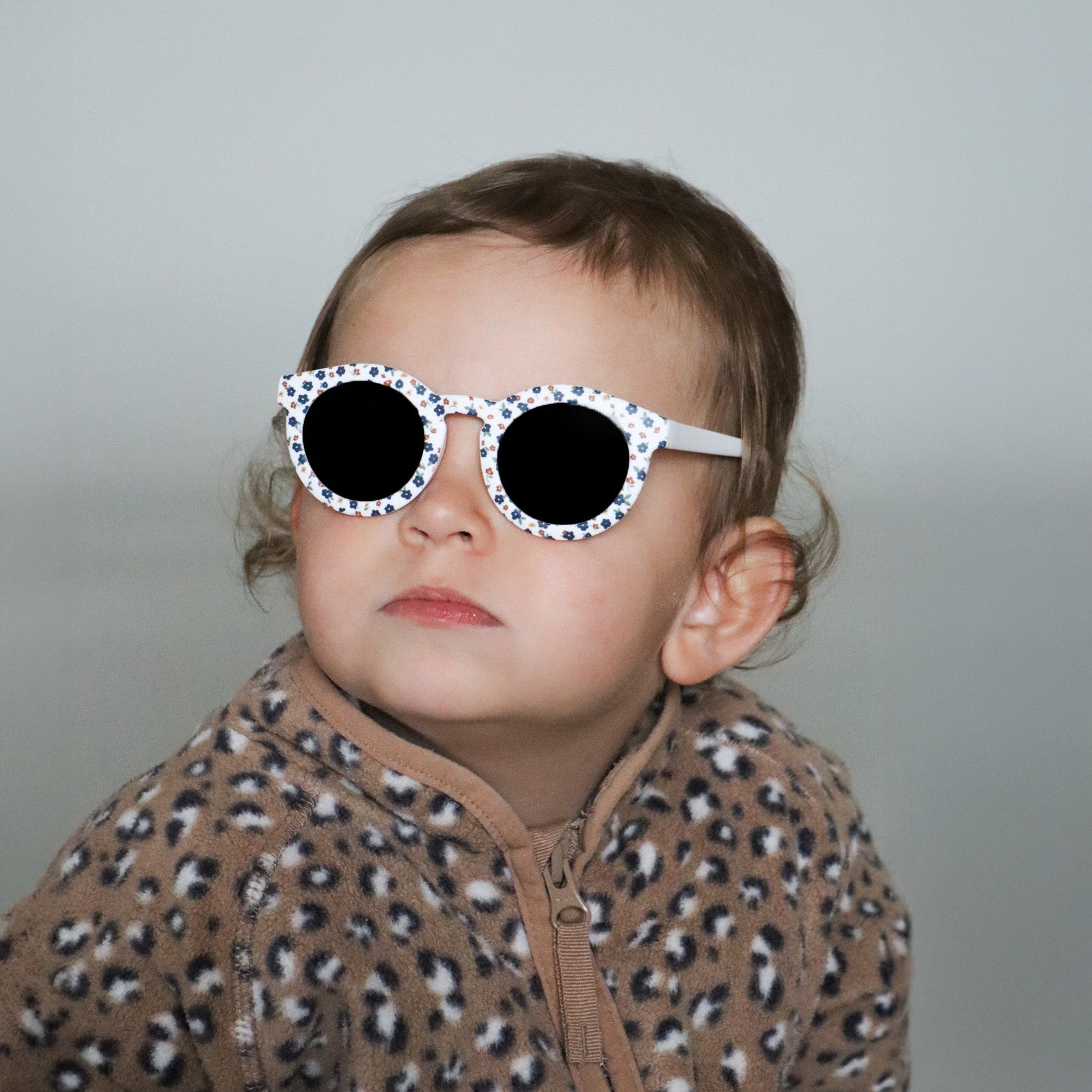 Paire de lunettes de soleil bébé catégorie 4, monture en TPEE blanc avec motif liberty fleuri. Mise en situation portée