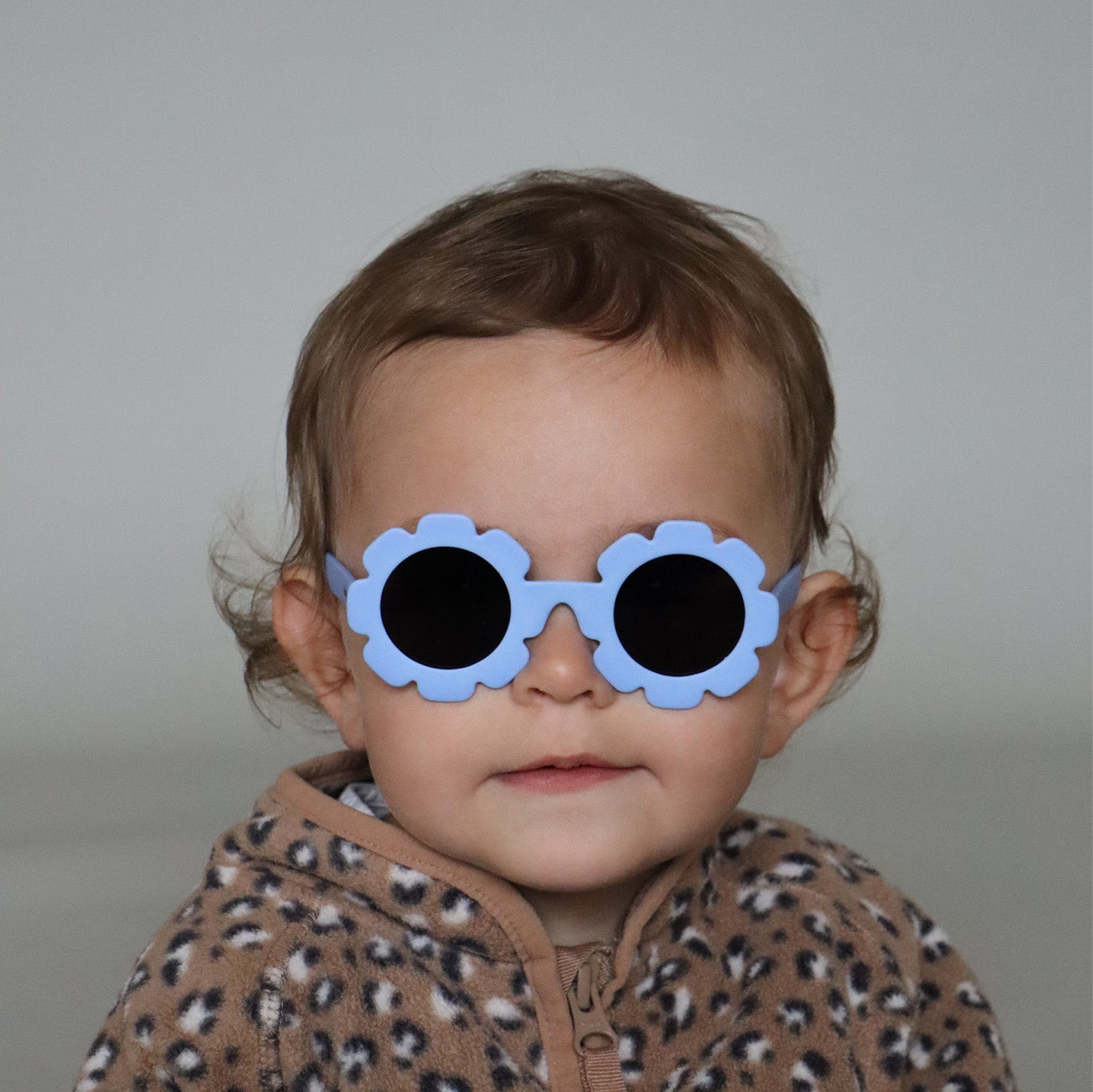 Paire de lunettes de soleil bébé catégorie 4, monture en TPEE bleue en forme de fleur. Mise en situation portée